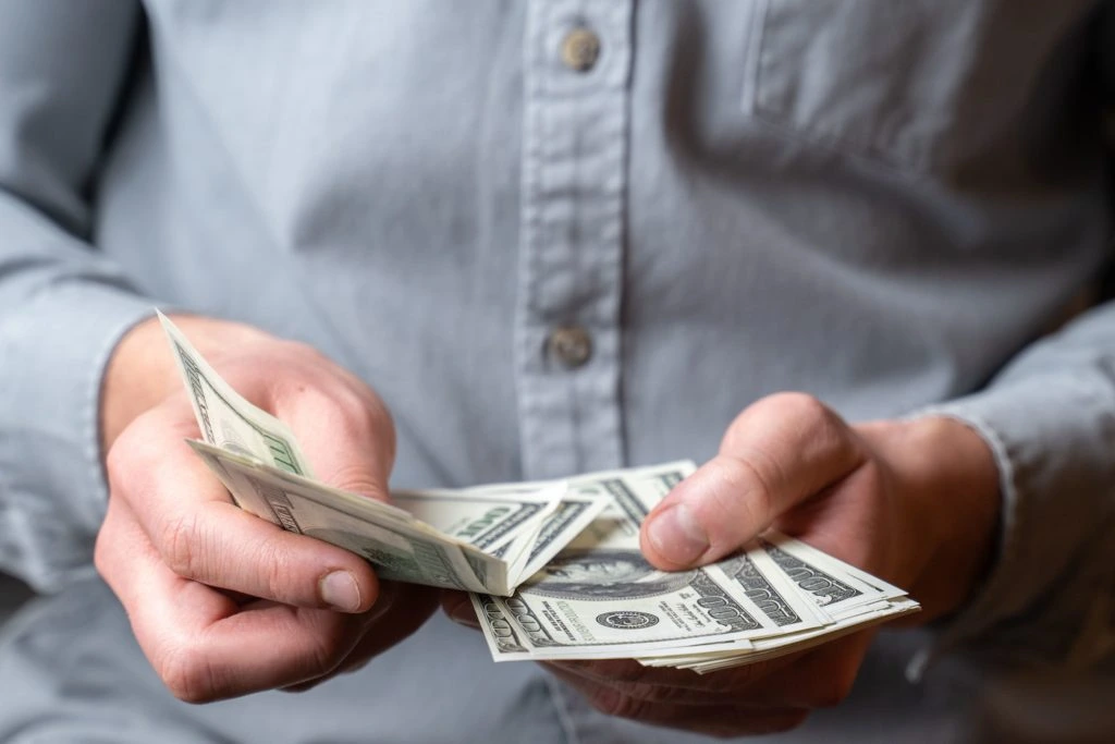 man counting his money made after selling on Walmart