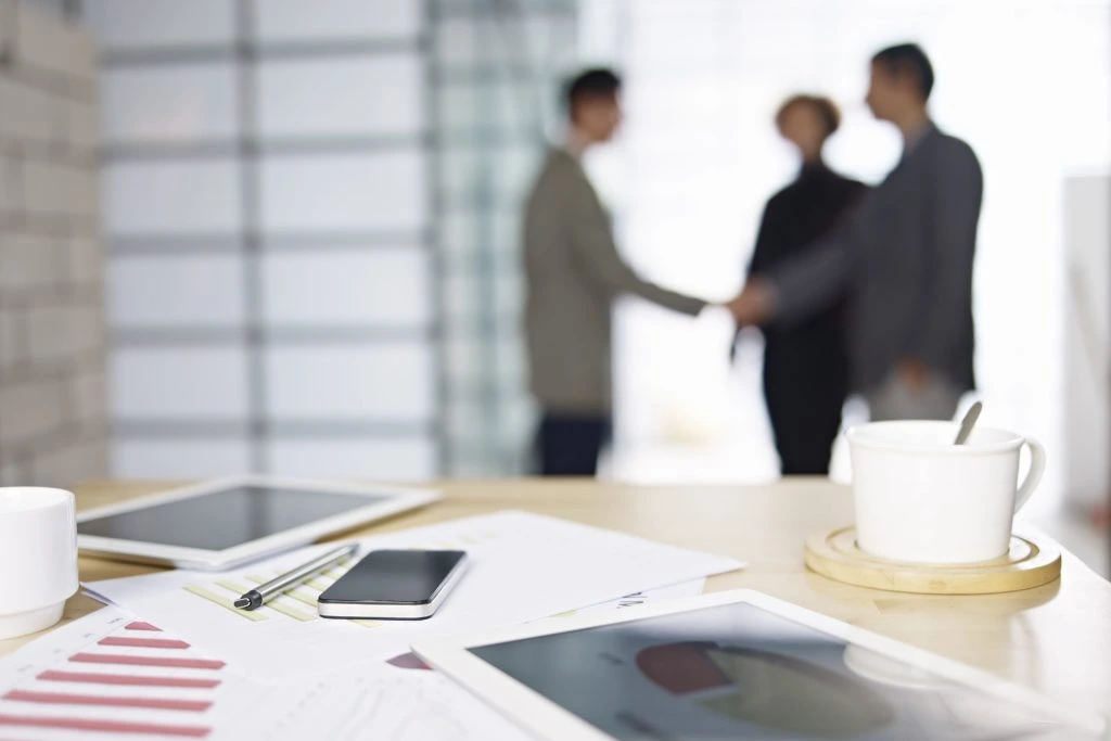 People making a business deal with paperwork and coffee in the foreground